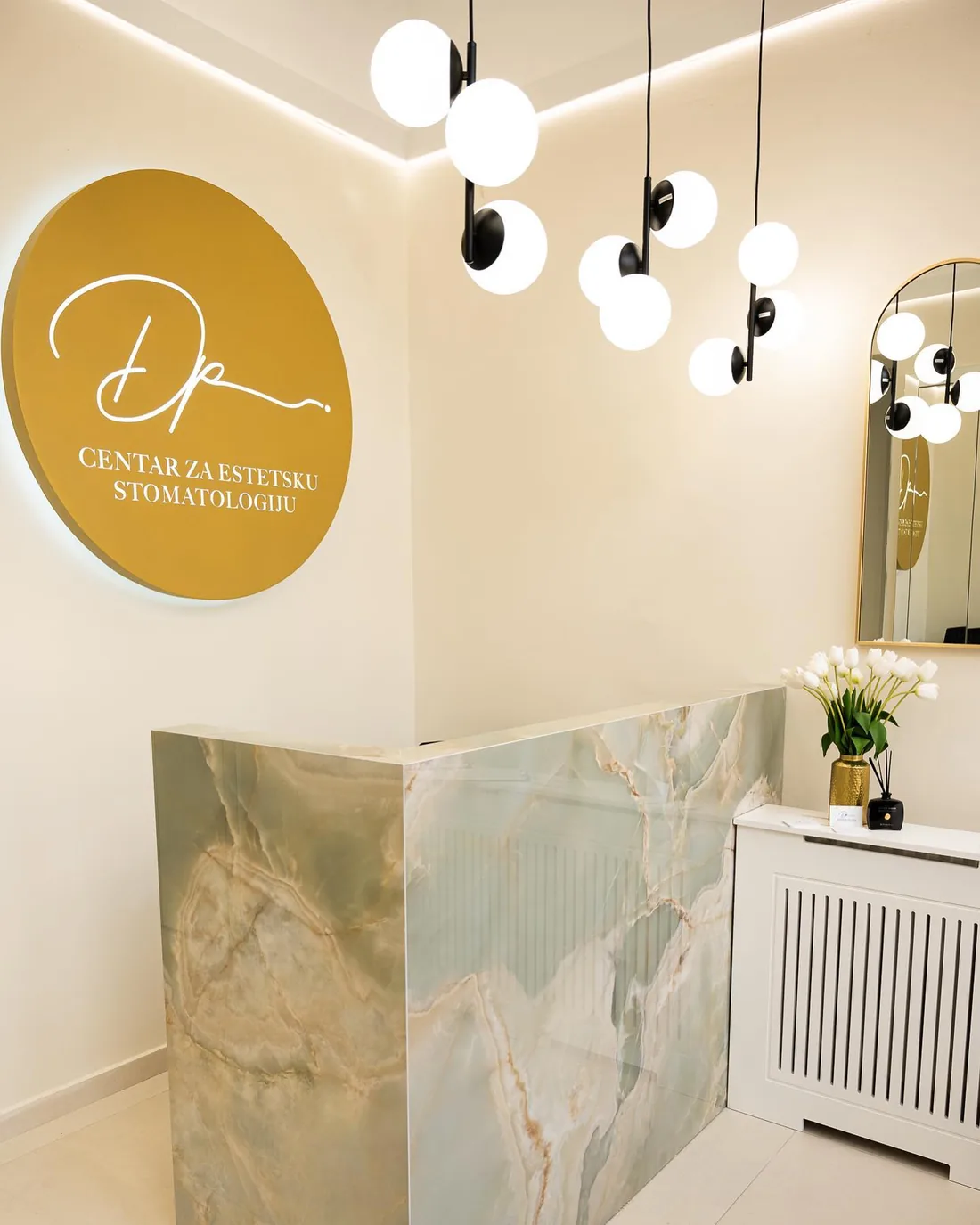 Recepcija Dental Plaze s osvijetljenim znakom i pultom od zelenog oniksa